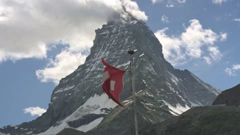 Swiss flag waving in the wind with the iconic matterhorn mountain peak Stockbeeldmateriaal 339097252