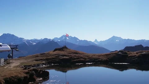 Swiss flag waving in the wind in idyllic mountain and lake scenery, aerial orbit Video stock 164674097