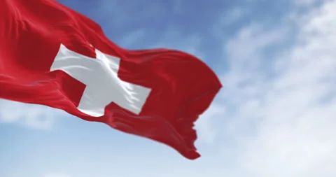 Swiss flag waving in the wind under a clear sky with white cross symbol Stock Footage 305754362