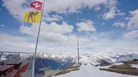 Swiss flags waving on snowy mountain top in the alps 스톡 동영상 310077447