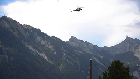 Swiss helicopter picking up payload, transporting it and dropping it off nearby Stock Footage 79810036