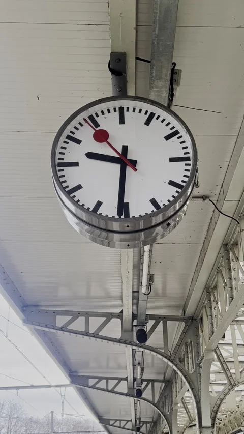 Swiss railway clock showing passing time at a train station platform Stock Footage 332143193