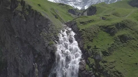 Swiss waterfall surrounded by snowy mountains Stockbeeldmateriaal 123711097