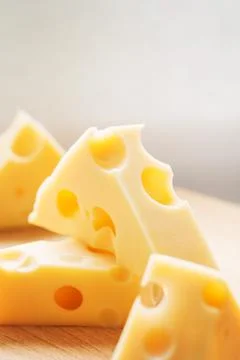 Swiss yellow cheese triangular chunks with holes on wooden plate. Maasdam Dut Stock Photos