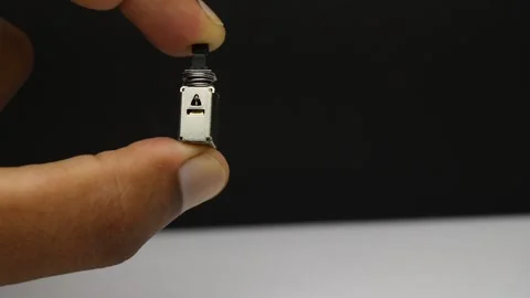 Switch component held in fingers showing the spring loaded button Stock Footage 344782118