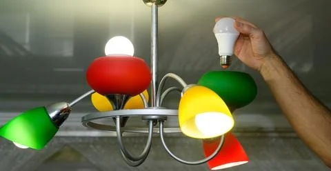 Switch from outdated lighting to LED shown as man fixes lamp. Lamp becomes .. Stock Photos