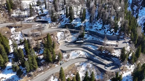 Switchback road stack winds forested mountainside white bus red cars van Stock Footage 345961397