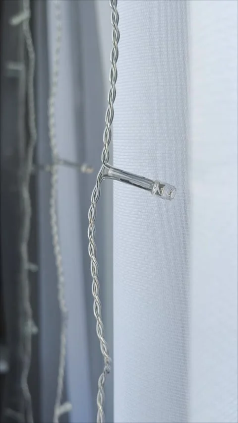 A switched-off LED garland hangs on a white tulle window. Interior decoration Stock Footage 313265697
