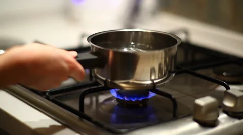 Switching on gas and placing stainless steel pot on gas oven Stock Footage