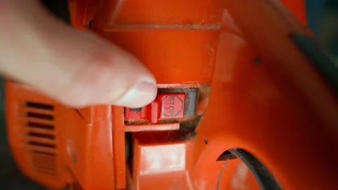 Switching the selector to the stop position on the body of the orange chainsaw Stock Footage 210499422