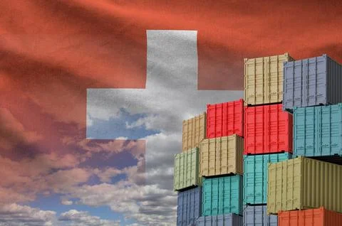 Switzerland flag and big stack of shipping cargo containers in docks with sky Stock Photos