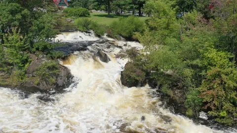 A swollen park river rages over rocks after a rain storm - pull away aerial Stock Footage 161332300