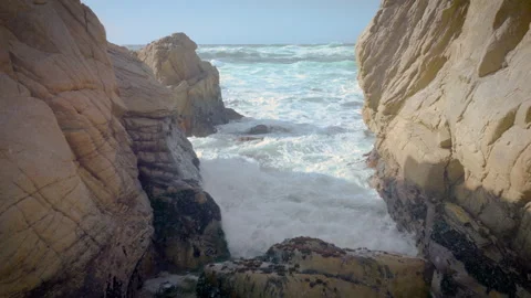 Swooping drone shot down through rocks to the sea Stock Footage 230548089