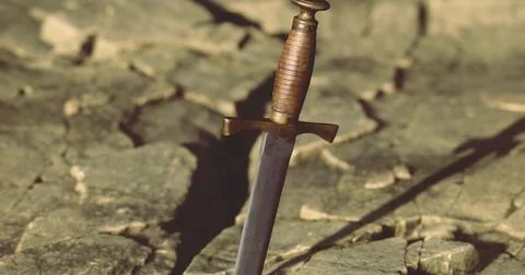 Sword embedded in cracked earth under sunlight in a barren landscape Stock Illustration