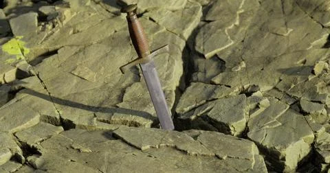 Sword embedded in rocky ground during daylight in a serene landscape Stock Illustration