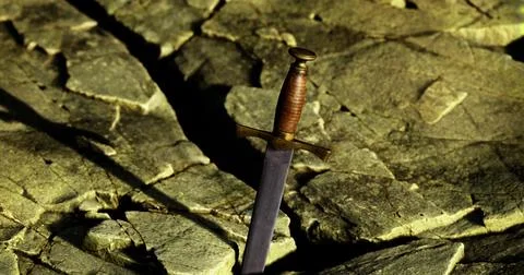 Sword embedded in rocky ground at dusk suggesting a mythical quest Stock Illustration