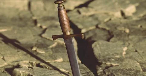 Sword embedded in rocky surface symbolizes strength and resilience Stock Illustration