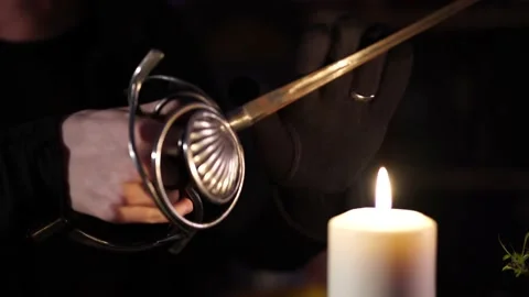 Sword glows over the flame of a wax candle 스톡 동영상 133077116