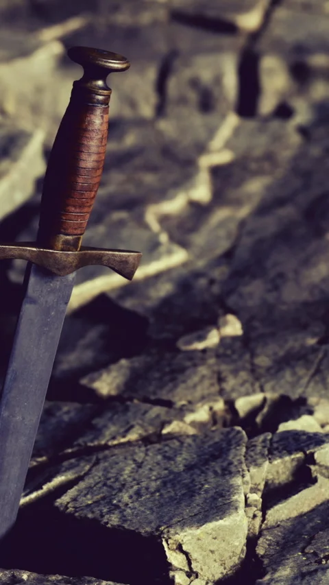 Sword rests on a rocky surface under soft natural light in an outdoor setting Stock Footage 335951720