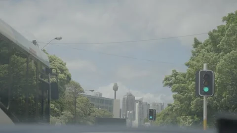 Sydney CBD Traffic Moving at Green Light on Urban Road with City Skyline View Stock Footage 341680207