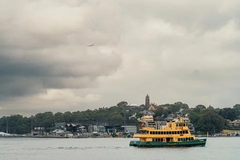 Sydney Ferry Sailing on the CBD Waterfront as an Airplane Flies Overhead Stock Photos