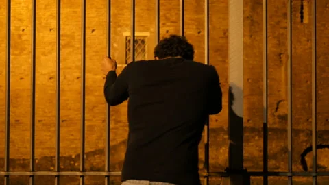 Symbol of captivity - man clings to the bars of a gate feeling trapped Vidéo 152642585