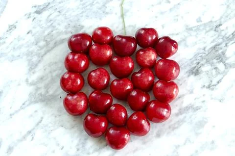 Symbol single cherry with stem on a marble table Stock Photos