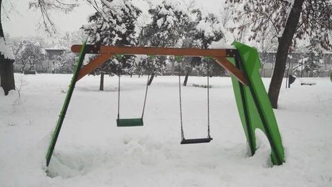 Symbolic shot with two empty swing while swinging in the snow park, close up. Video stock 101264675