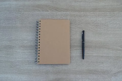 Symmetric flat lay of kraft notebook and pen on wooden background, work-lif.. Stock Photos