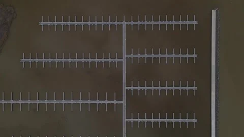 A symmetrical aerial view of empty floating docks extending into calm, dark Stock Footage 303416157