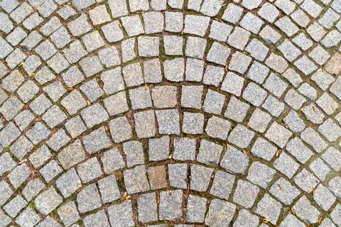 Symmetrical cobblestone pattern with slight moss in circular plaza Stock Photos