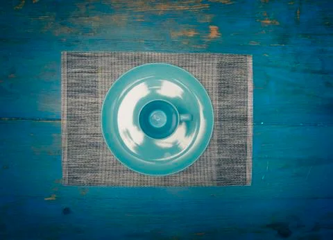 Symmetrical composition of an empty plate and cup on blue table zenith view Stock Photos