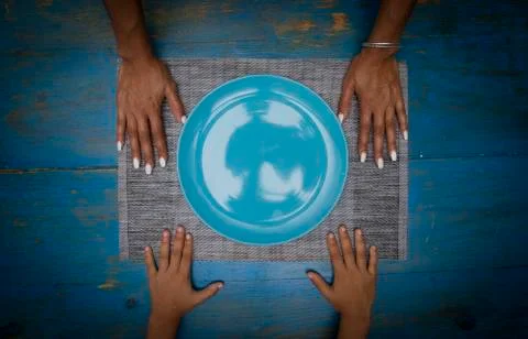 Symmetrical composition of four hands on a blue table and empty dish or plate Stock Photos