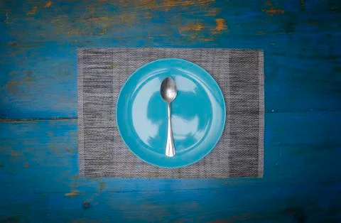 Symmetrical composition of one empty blue dish and spoon on a blue table zeni Stock Photos