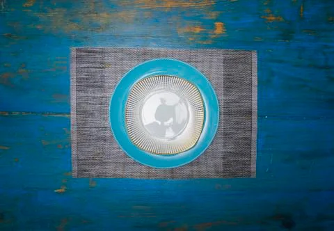 Symmetrical composition of one empty plate on a blue table Stock Photos