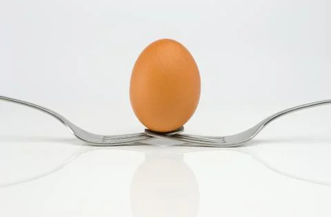 Symmetrical composition of two forks and an egg. Stock Photos