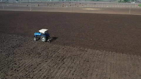 Symmetrical high angle drone perspective tracking a solitary blue tractor Stock Footage 337191707