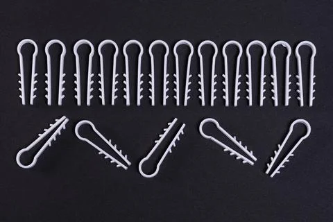 Symmetrical pattern of white plastic fasteners on black background Stock Photos