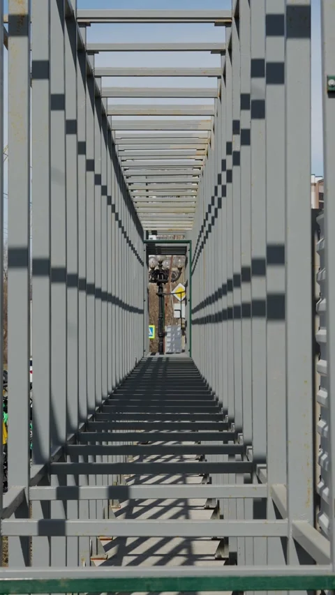 Symmetrical perspective of repeating grey metal frame structures in sunlight Stock Footage 332433591