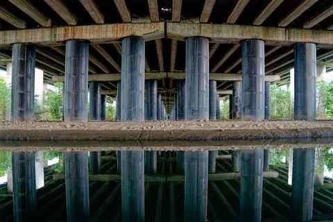 Symmetrical Reflection of Bridge Pillars in Water Beneath Elevated Overpass Stock-Fotos