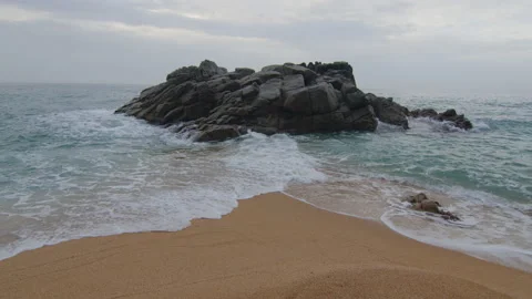 Symmetrical shot of the sea separated in two at the edge of the beach with rocks Stock Footage 230097349