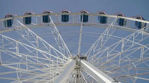 Symmetrical view of blue cabins arranged of a large white observation wheel. Stock Footage 340333594