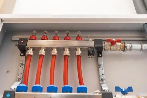 Symmetrical view of heating manifold with multiple red pipes inside cabinet. Fotos de archivo