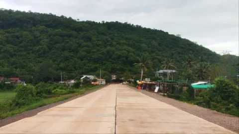 Symmetrical View of Straight Concrete Road Leading to Mountain Village Stock Footage 343774946