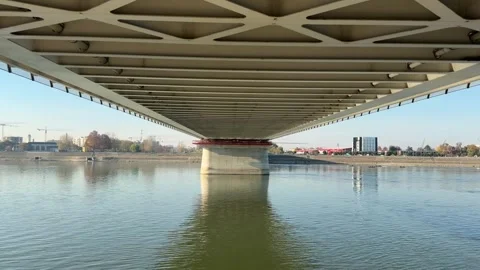 Symmetrical view underneath large bridge over wide river reflecting Stock Footage 329306011