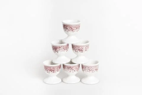 Symmetrically stacked ceramic egg cups with a reddish pattern on a white Stock Photos