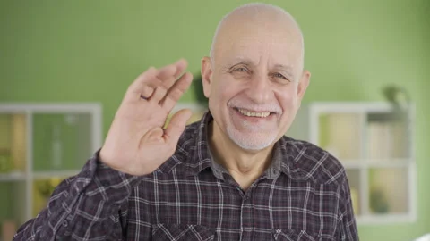 Sympathetic old man smiling looking at camera and waving, saying hello. Stock-Footage 232239541