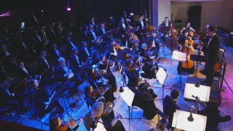 A symphony orchestra performs on stage with performers playing violins, cello Stockbeeldmateriaal 149980953