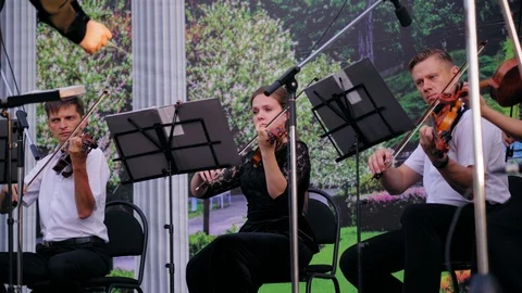 Symphony orchestra viola and second violin section performing in park in evening Stock Footage 110595847