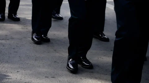 A synchronized procession featuring individuals in formal dark trousers and Stock Footage 312510999